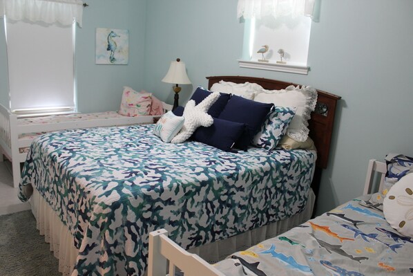 A bedroom with a bed, a nightstand, a lamp, and a window with curtains.