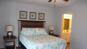 A bedroom with a wooden headboard, a bed with a patterned bedspread, two bedside tables with lamps, and a ceiling fan. - Pelican Point #10 - Beautiful Complex, Gorgeous Sunrises & Easy Access (Port Mansfield)