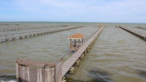Eine Holzstege, der sich in ruhiges Wasser erstreckt, mit einem kleinen Unterstand am Ende.
