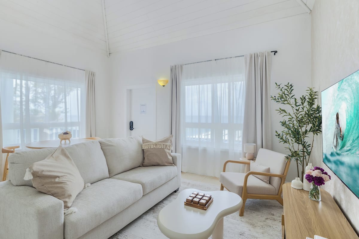 A modern living room with a sofa, armchairs, a coffee table, and a painting on the wall.