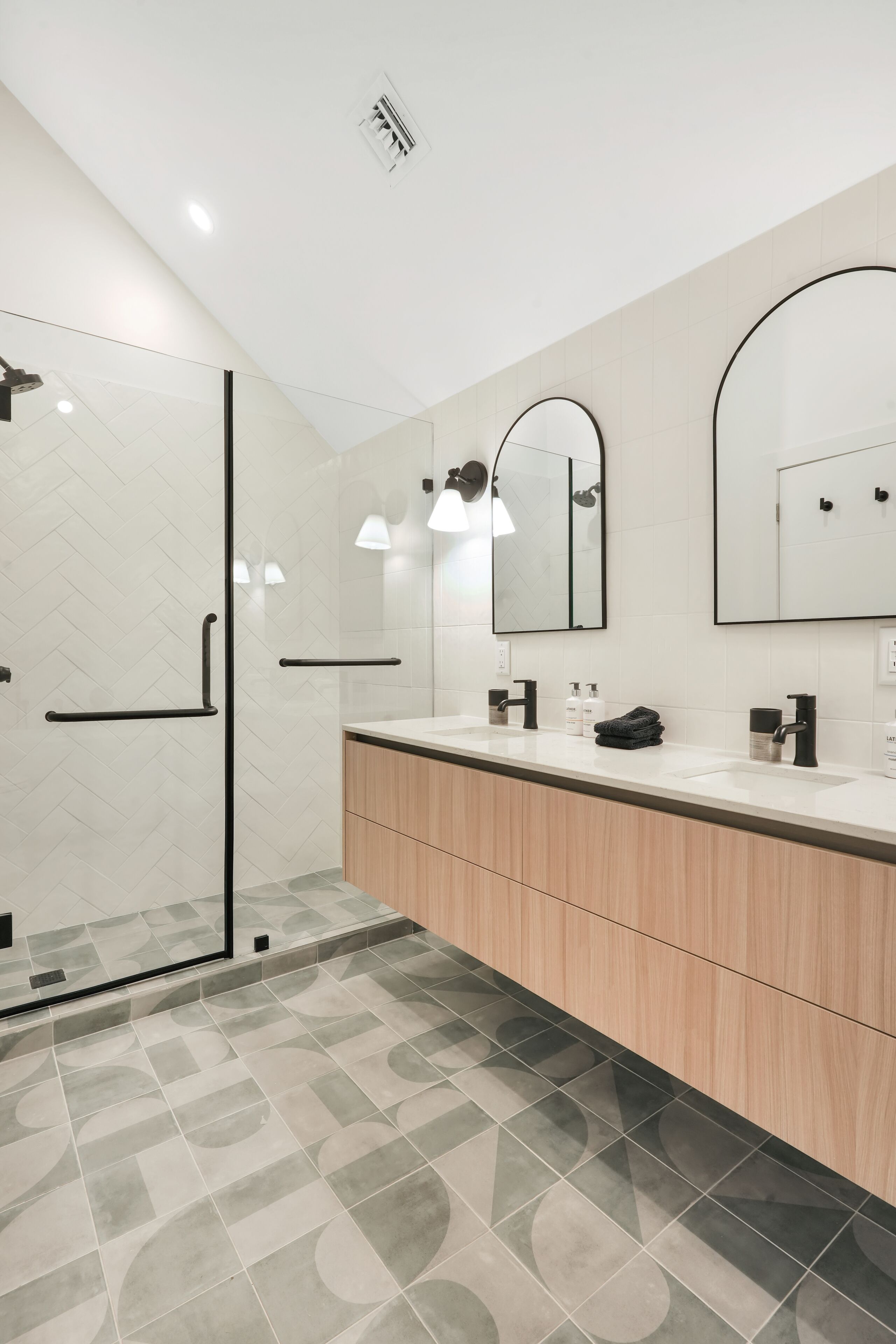 A modern bathroom with a glass shower enclosure, a double sink vanity, and a large mirror.