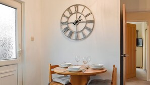 A dining area with a round wooden table, four chairs, and a wall-mounted clock. - 2 bedroom accommodation in Sockbridge, near Ullswater (Sockbridge, near Ullswater)