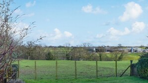 A rural landscape with a fenced field, a wooden fence, and a distant building. - 2 bedroom accommodation in Sockbridge, near Ullswater (Sockbridge, near Ullswater)