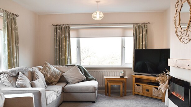 A living room with a grey sofa, a television, a small wooden table, and a fireplace. - 2 bedroom accommodation in Sockbridge, near Ullswater (Sockbridge, near Ullswater)