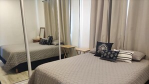A bedroom with two beds, a mirror, a small table, and a chair. - Loft en Laureles, Coworking y Desayuno Incluido (Medellín)