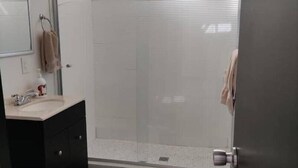 A modern bathroom with a glass shower enclosure, a sink with a mirror, and a toilet. - Loft en Laureles, Coworking y Desayuno Incluido (Medellín)