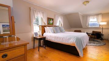Une chambre à coucher comprenant un lit, une commode en bois, une table de chevet et un bureau avec une chaise.