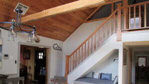 A spacious living area with a wooden staircase, a dining table with chairs, and a cozy seating area with cushions. - Whitetail Ridge (Cadiz)