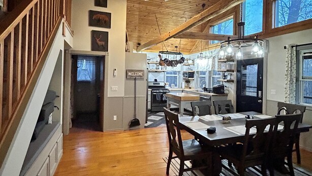 A spacious kitchen with wooden floors, a dining area with a table and chairs, and a staircase leading to an upper level. - Whitetail Ridge (Cadiz)