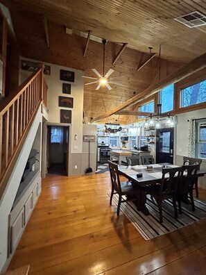 Une cuisine spacieuse avec un plancher en bois, un coin repas avec une table et des chaises, et un escalier menant à l’étage supérieur.