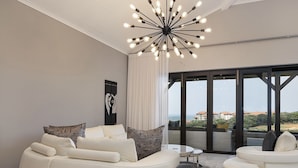 A modern living room with a white sofa, a round coffee table, and a unique ceiling light fixture.