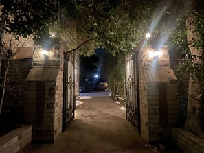 A nighttime entrance with stone walls and metal gates, leading to a dimly lit path. - Malek Pyramids Guest House (Giza)