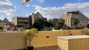 Une terrasse sur le toit offrant une vue sur les pyramides, un restaurant et un bâtiment orné de hiéroglyphes.