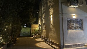 Un étroit sentier menant à un bâtiment doté d’un escalier et d’une entrée fermée par un portail.