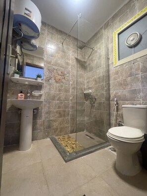 A bathroom with a glass-enclosed shower, a pedestal sink, a toilet, and a decorative tile backsplash. - Malek Pyramids Guest House (Giza)