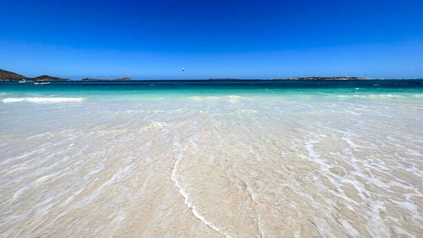 Une plage à l’eau turquoise et au sable blanc.