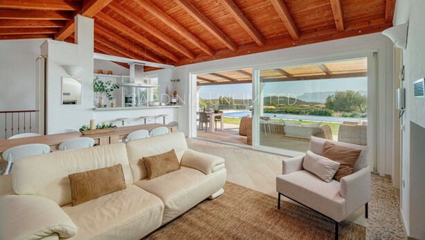 A spacious living area with a wooden ceiling, a sofa, a chair, and a dining table.