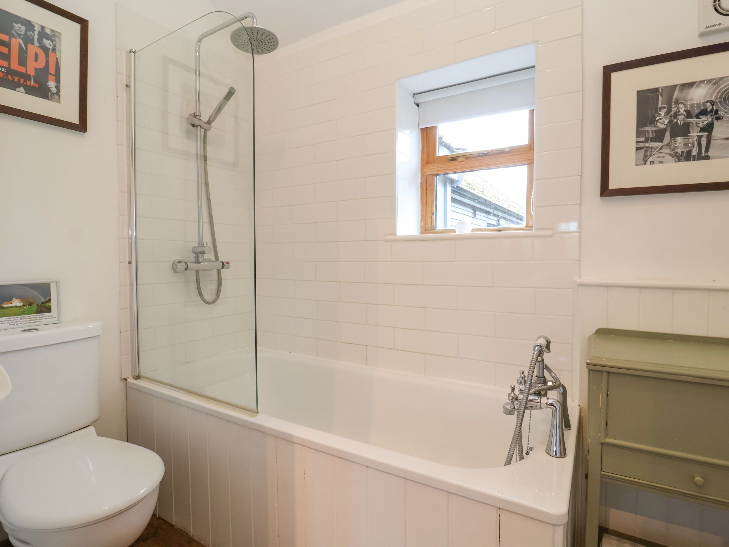 A bathroom with a glass-enclosed shower, a bathtub, a toilet, and a small window.