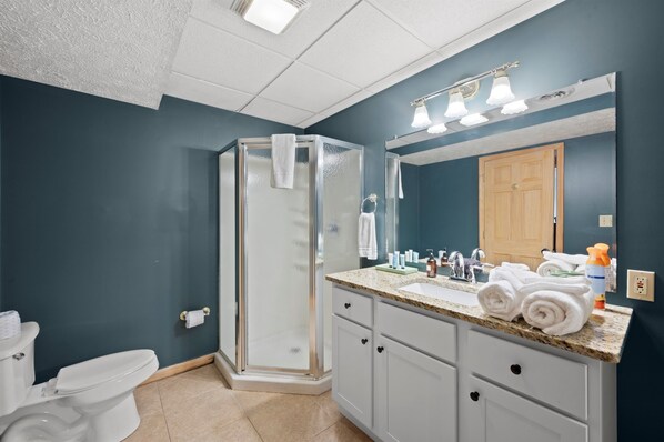 Une salle de bain avec une douche à parois de verre, un lavabo avec un miroir et des toilettes.