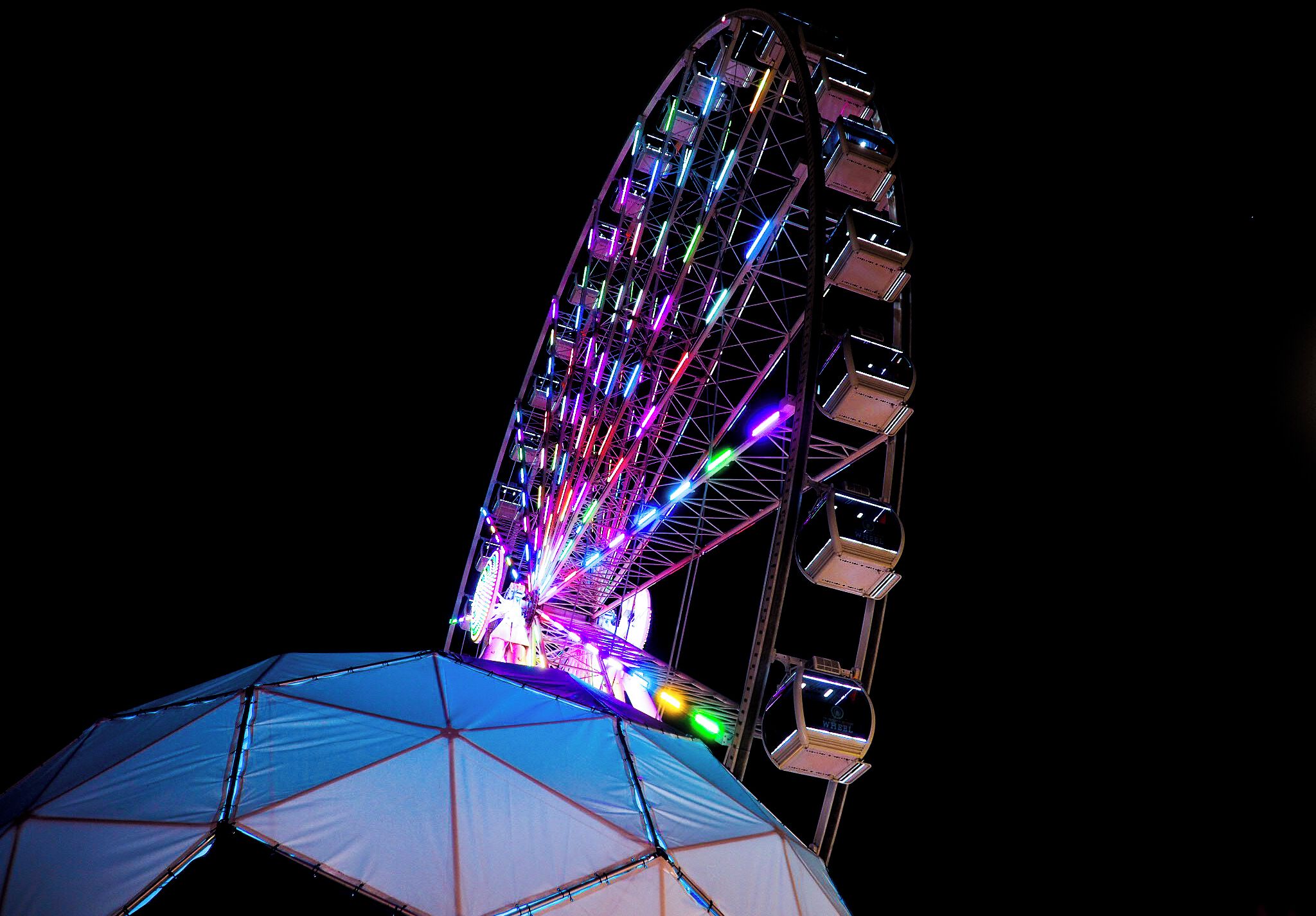 A large Ferris wheel with colorful lights against a dark sky.
