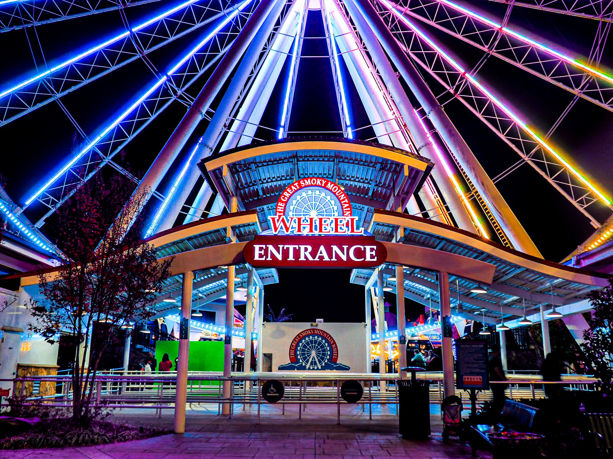 Entrada para a Great Smoky Mountain Wheel, com uma grande roda gigante e sinalização iluminada.