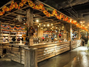 A rustic interior with wooden beams, a central counter, and hanging autumn leaves. - Cozy Hot Tub Chalet | Minutes to The Island (Pigeon Forge)
