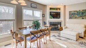 A dining area with a wooden table and chairs, a fireplace, a sofa, and a TV mounted above the fireplace. - Large Tazewell Home < 1 Mi to Norris Lake Access! (Tazewell)
