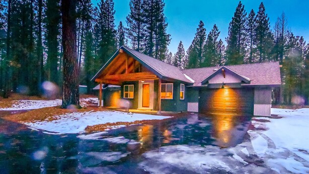 A cabin with a wooden exterior, a front porch, and a garage.