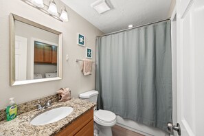 A bathroom with a granite countertop sink, a white toilet, and a shower curtain. - 
Cozy 2-Bedroom Condo in Prime Siesta Key Location (Sarasota)
