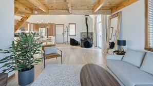 Un vaste espace de vie doté d’un plafond en bois, d’un canapé, d’une table basse et d’une plante en pot.