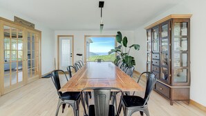 Comedor con mesa de madera, sillas de metal, un aparador y vista al exterior.