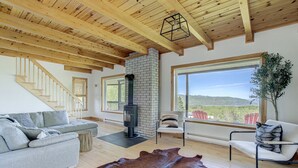 Una sala de estar moderna con chimenea de piedra, un sofá, un tapete de cuero y vistas al exterior.
