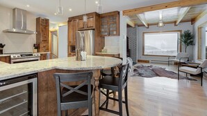 Una cocina moderna con una isla central, armarios de madera, electrodomésticos de acero inoxidable e iluminación colgante.