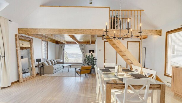 Un vaste espace de vie comprenant un escalier en bois, une table à manger avec des chaises et un canapé.