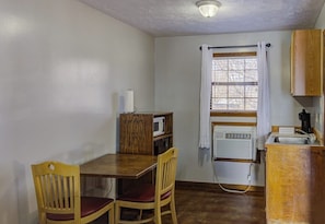 A compact kitchen with a wooden table, two chairs, a microwave, and a sink.