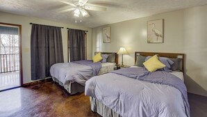 A bedroom with two beds, a ceiling fan, and a door leading to a balcony.