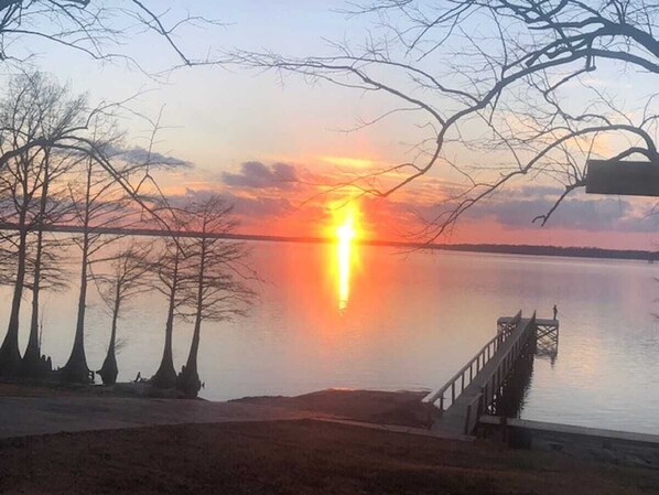 Ein Sonnenuntergang über einem ruhigen See, mit einem Steg, der sich ins Wasser erstreckt.