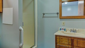 A bathroom with a shower, toilet, and vanity with a mirror.