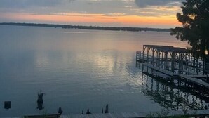 A calm lake at sunset with a dock and grassy area. - Sunset View RV Spot 30 AMP (Vicksburg)