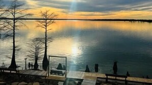 A lakeside view with a wooden dock, a bench, and a gazebo. - Sunset View RV Spot 30 AMP (Vicksburg)