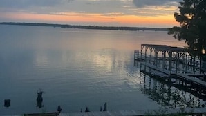 A calm lake at sunset with a dock and grassy area. - Eagle Lake RV Spot 50AMP, Private Boat Ramp (Vicksburg)