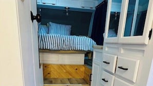 Een kleine kamer met een bed, een kledingkast en een klein raam.