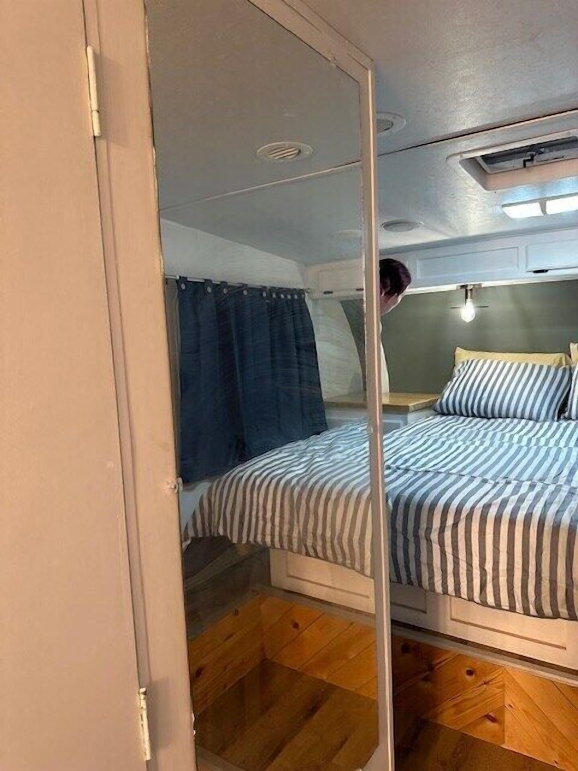 A compact bedroom with a bed, a window with curtains, and a ceiling light.
