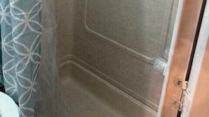 Een badkamer met een douchecabine, toilet en een douchegordijn met een patroon.