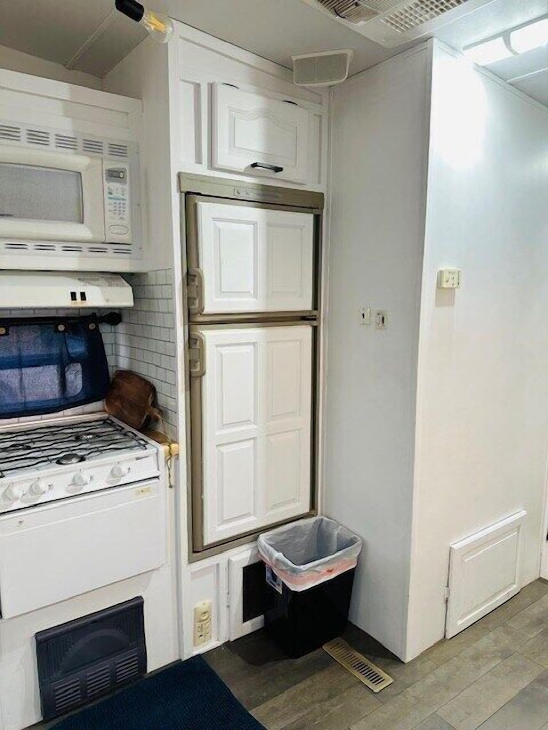 Cocina compacta con microondas, horno y refrigerador de dos puertas.