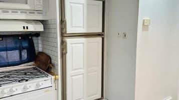 A compact kitchen with a microwave, oven, and a double door refrigerator.