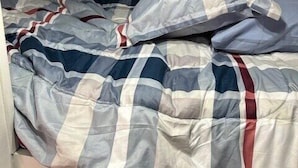 Un lit avec une couvre-lit à carreaux et une tête de lit sombre.