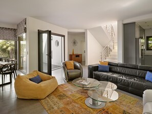 A modern living room with a glass coffee table, leather sofa, and a yellow bean bag.