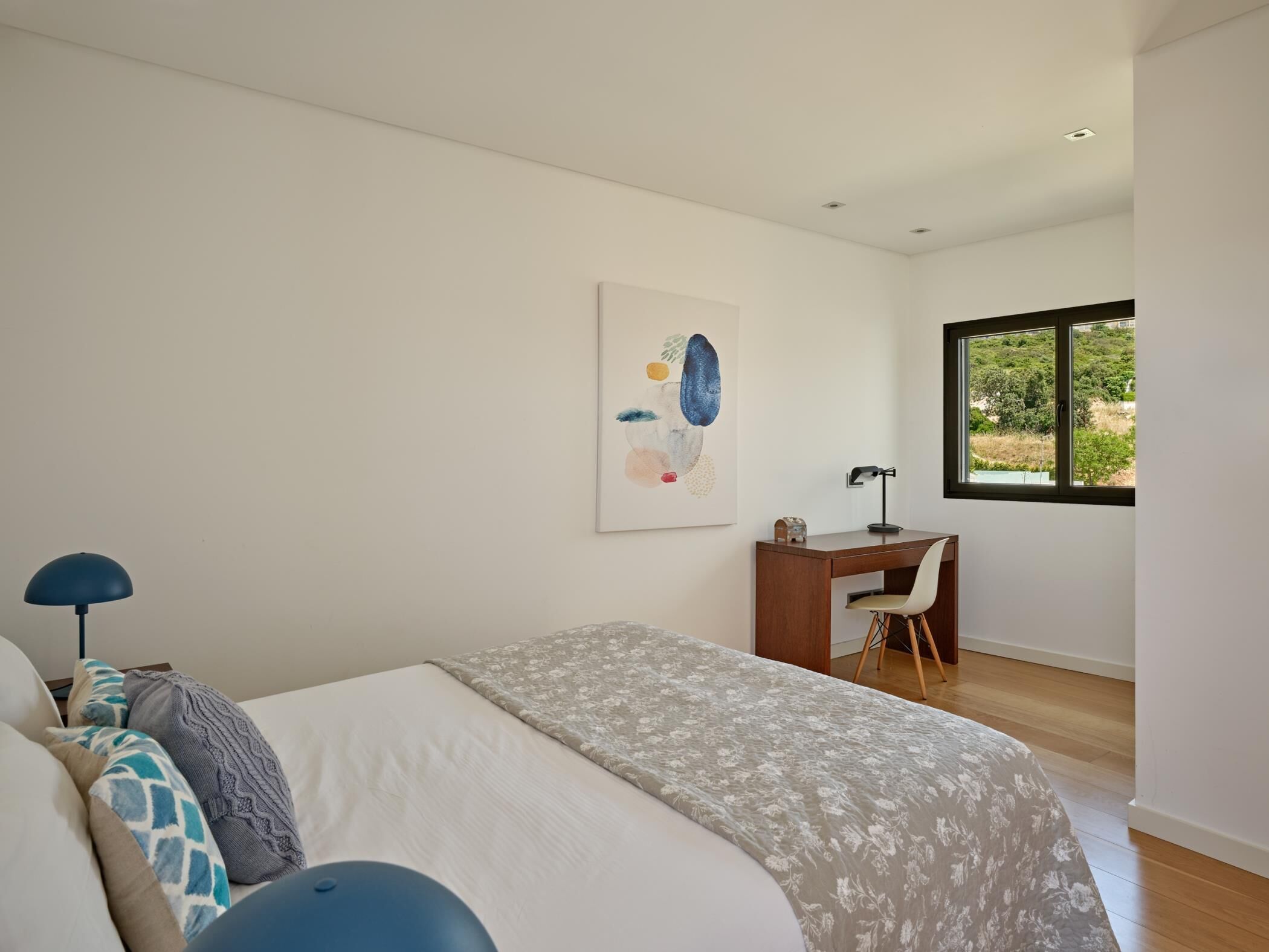 Een slaapkamer met een bed, bureau en raam.