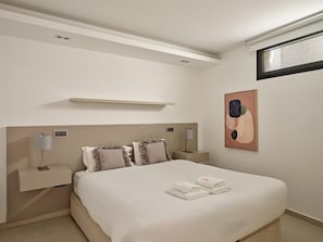 A modern bedroom with a bed, bedside tables, a lamp, and a painting.
